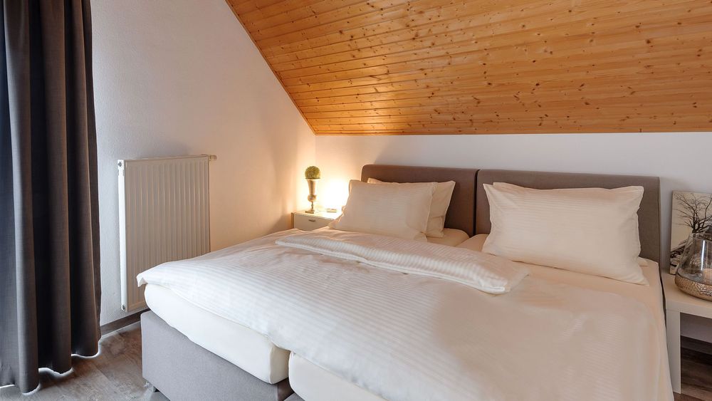 Schlafzimmer mit Doppelbett, Holzdecke und Nachttisch mit Lampe.