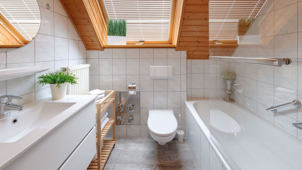 Badezimmer mit Badewanne, Waschbecken und Holzdecke unter zwei Dachfenstern.