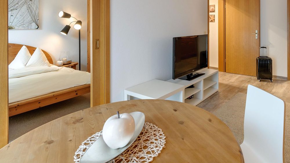 Detailaufnahme eines Esstisches mit Dekoschale, weißem Apfel und Tischlampe im Hintergrund.