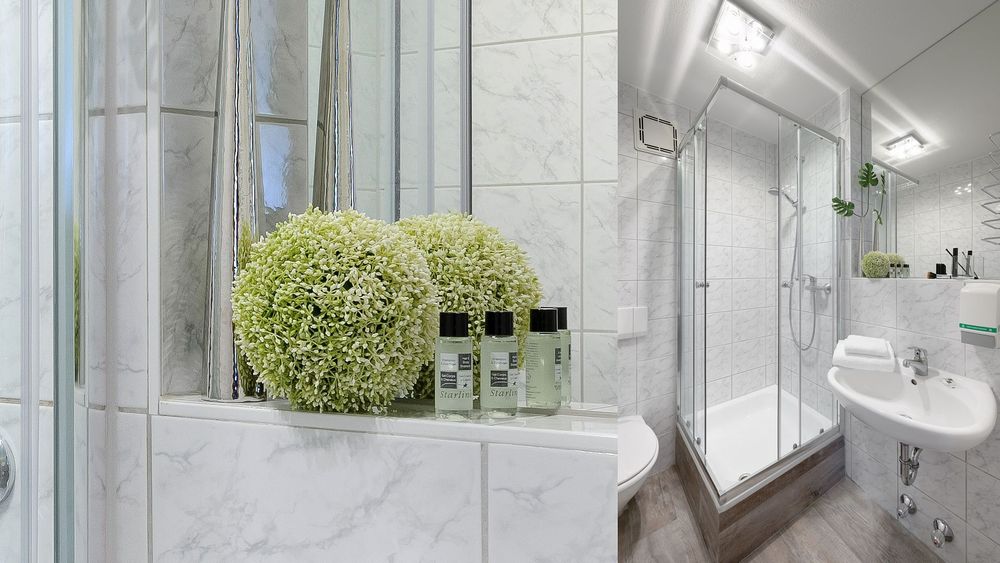 Modernes Badezimmer mit Duschkabine, weiß gefliesten Wänden und kleinen Pflegeprodukten auf dem Regal.